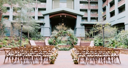 Two sections of chairs pointed towards a flower adorned altar and separated by an aisle strewn with rose petals