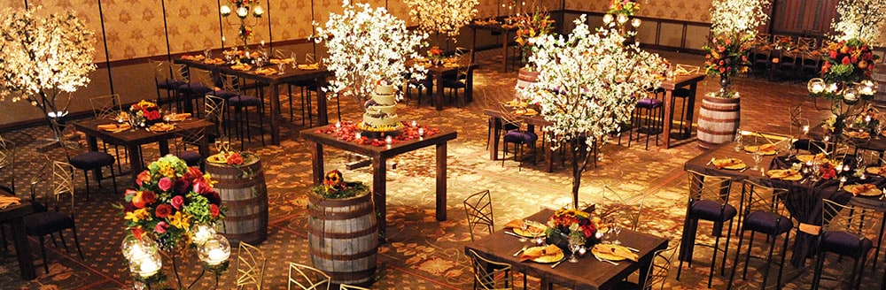 A rustic room decorated with small trees and floral arrangements