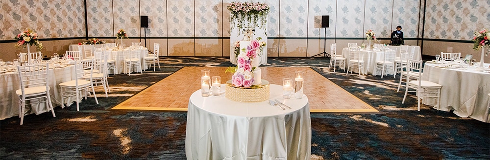 A cake table rests at the end of a dance floor in a reception hall