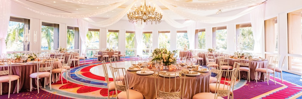 A chandelier hanging from the center of a room holding several round tables