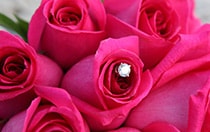 A diamond shaped charm in the middle of a rose bouquet