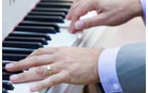 A pair of hands are positioned on a piano keyboard, playing a chord