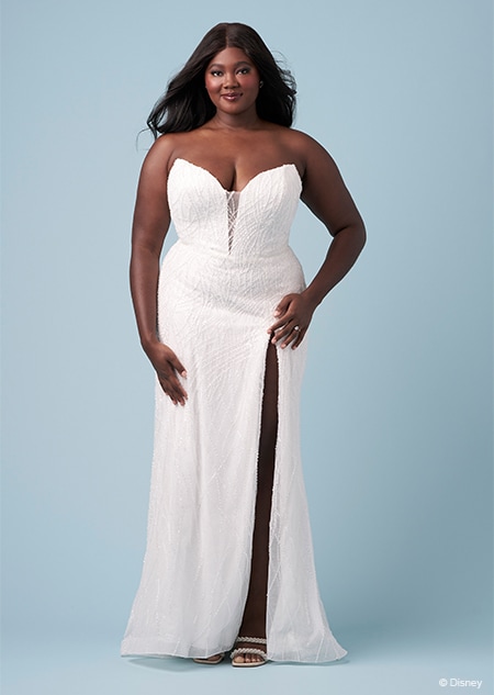 A bride wearing a strapless Ariel inspired sheath gown featuring an illusion neckline and a high slit