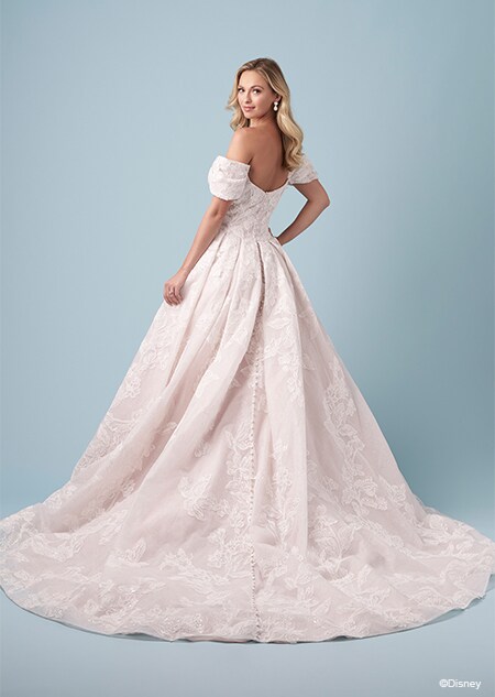 A bride wearing an Aurora inspired A line wedding gown featuring embroidery and off the shoulder sleeves