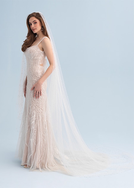 A woman wearing a veil and a wedding dress covered with beaded patterns