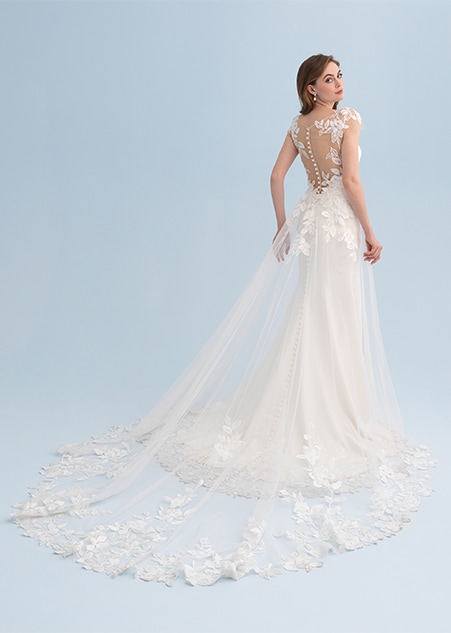 A woman looking over her shoulder wearing a wedding dress with a long train