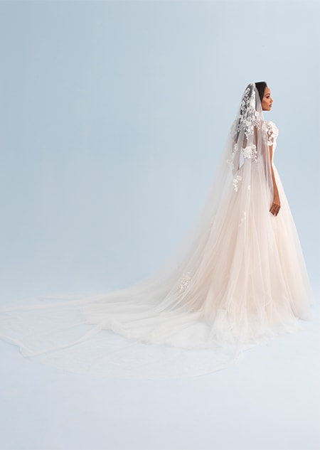 A woman looking over her shoulder wearing a wedding dress with a lacy veil