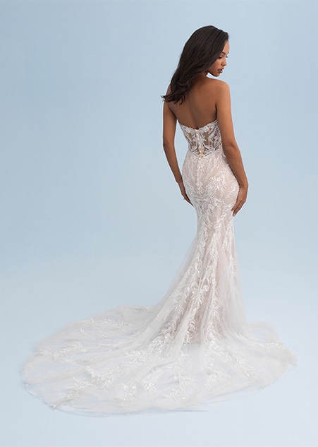 A woman looking over her shoulder wearing a form fitting and lacy strapless wedding dress A woman looking over her shoulder wearing a form fitting and lacy strapless wedding dress
