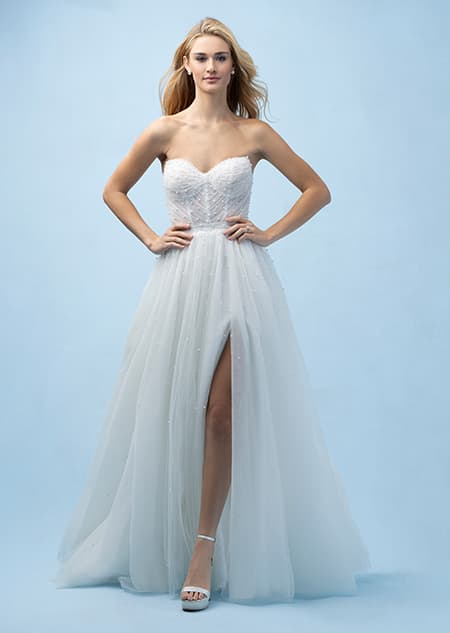 The front of a bride wearing an Ariel inspired A line gown featuring a sweetheart neckline, lightly beaded fabric and a high slit in the skirt