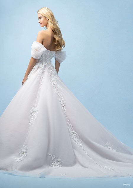 The back of a bride wearing a Rapunzel inspired A line gown featuring off the shoulder sleeves, a train and lace flowers on the bodice and skirt