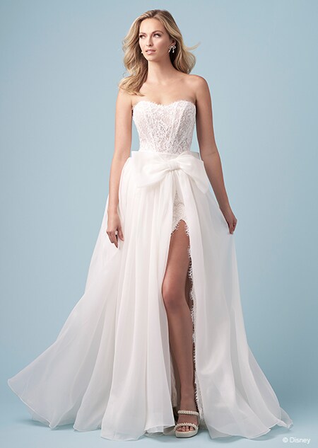 A bride wearing a strapless Snow White inspired sheath dress featuring an embroidered bodice and a high slit