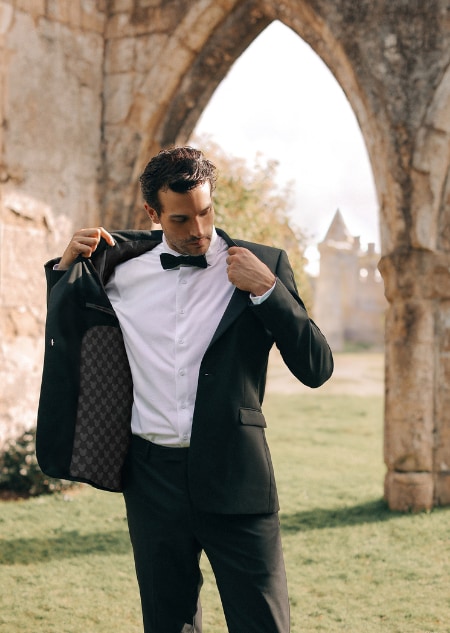 A man in a black tuxedo opening his jacket to reveal a Mickey Mouse patterned lining