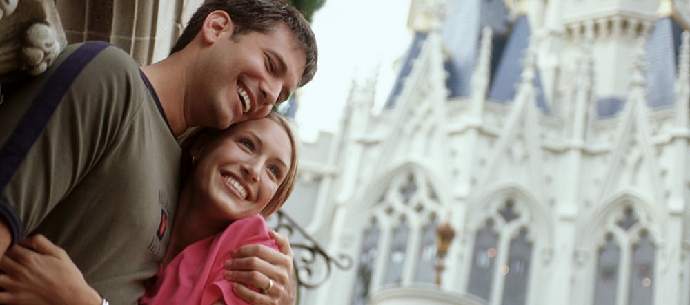 A man and woman embrace by Cinderella Castle at Magic Kingdom park in Florida