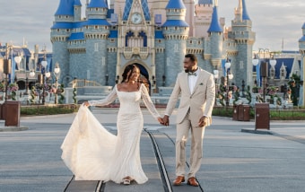 A vow renewal couple walking hand in hand near Cinderella Castle at Magic Kingdom Park