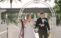A happy bride and groom walk across a bridge
