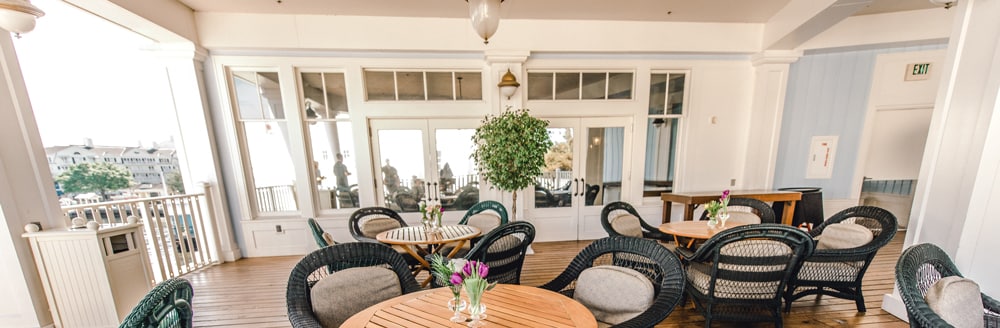 Wicker chairs surround small circular tables on a patio