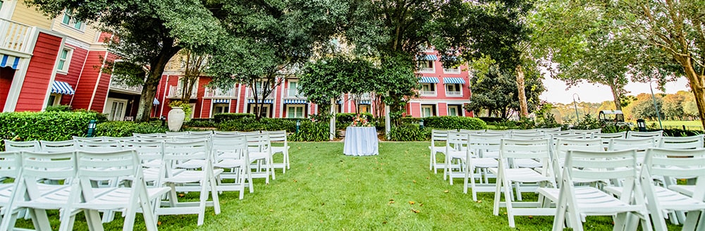 An aisle leading to a small round table on a lawn with trees in the background