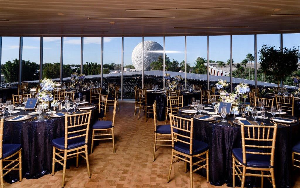 Circular tables arranged in a room with long clear windows showing a view of Spaceship Earth