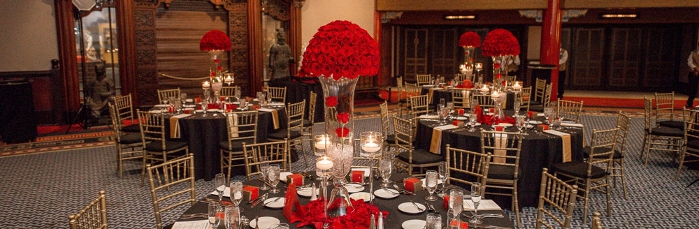 Round tables with place settings and large bouquets of roses as centerpieces