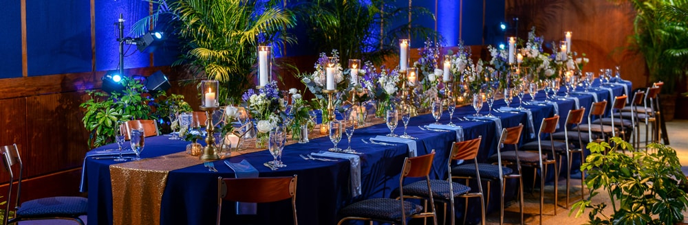 A long table holding several vases of flowers, candles, water glasses and champagne flutes