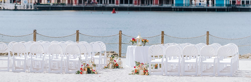 A round table on a beach facing a body of water and Disney’s BoardWalk