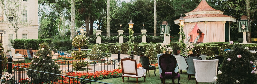 Armchairs on a lawn in front of a hege and canopy decorated for a ceremony