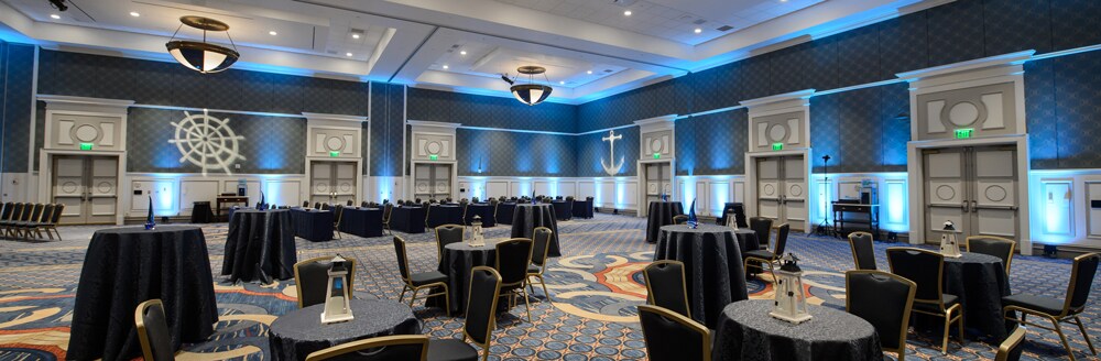 A large light fixture hangs from the ceiling over several small circular tables
