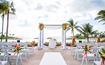 Floral arrangements adorn a wedding altar on a patio overlooking the ocean
