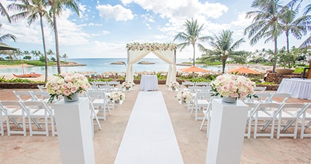 Two sections of chairs pointed towards a flower adorned altar and the ocean