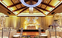 An elaborate light fixture hanging in the center of large room with many round tables and chairs
