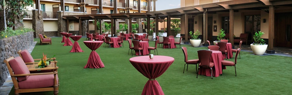 Several tables arranged on a lawn near a hotel building