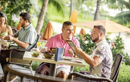 Two men check out the menu over a meal at Aulani A Disney Resort & Spa
