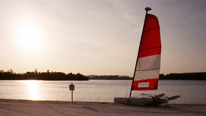 A sailboat on the sand by a lake