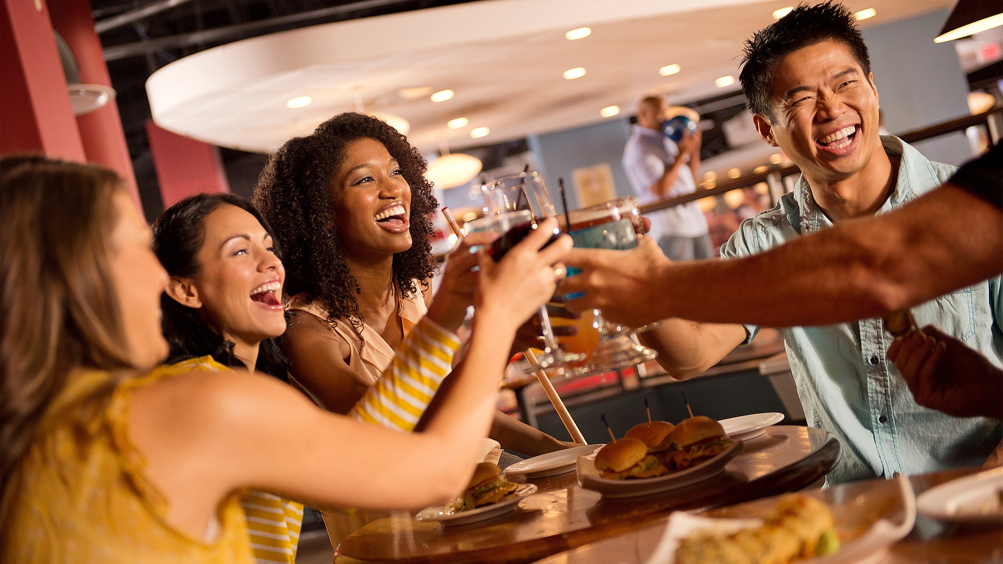 A group of friends at a dinner table, raising their glasses for a toast