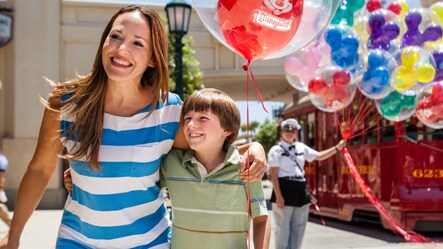 A woman and son walking by a balloon vendor at Disneyland Resort in California