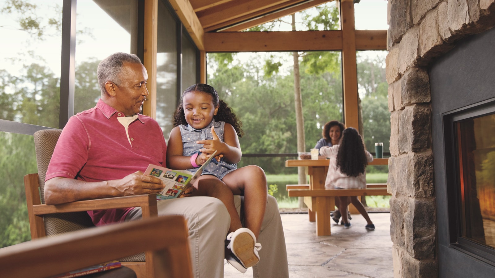 A grandfather, his daughter and 2 granddaughters relax in an outdoor living area