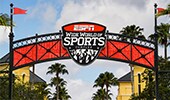 An arched sign that reads ESPN Wide World of Sports Complex with pennants on both sides at the entrance to ESPN Wide World of Sports Complex at Walt Disney World Resort in Florida