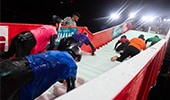 Participants in soaped up wetsuits attempting to climb slippery stairs in a competitive event on ESPN8, The Ocho