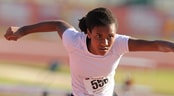 AAU Primary National Championships A female sprinter jumps a hurdle on a track