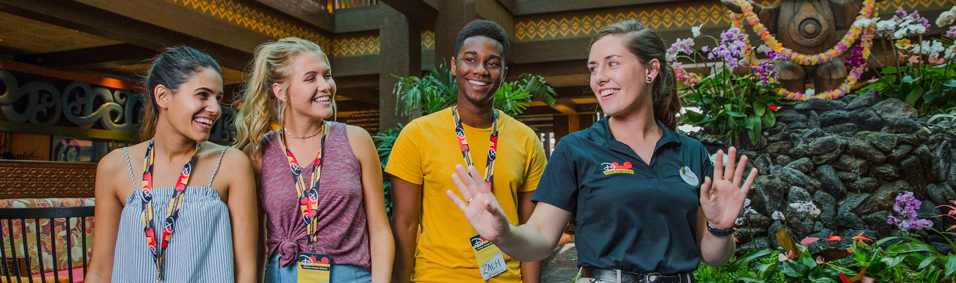 A female Disney staffer talks with 2 female students and 1 male student in a Disney Resort hotel
