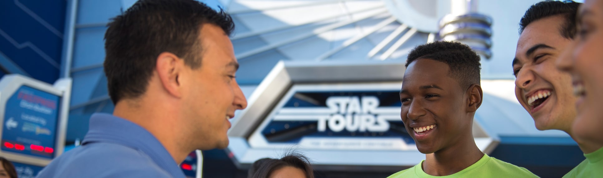 Two boys share a laugh with an adult by the Star Tours attraction